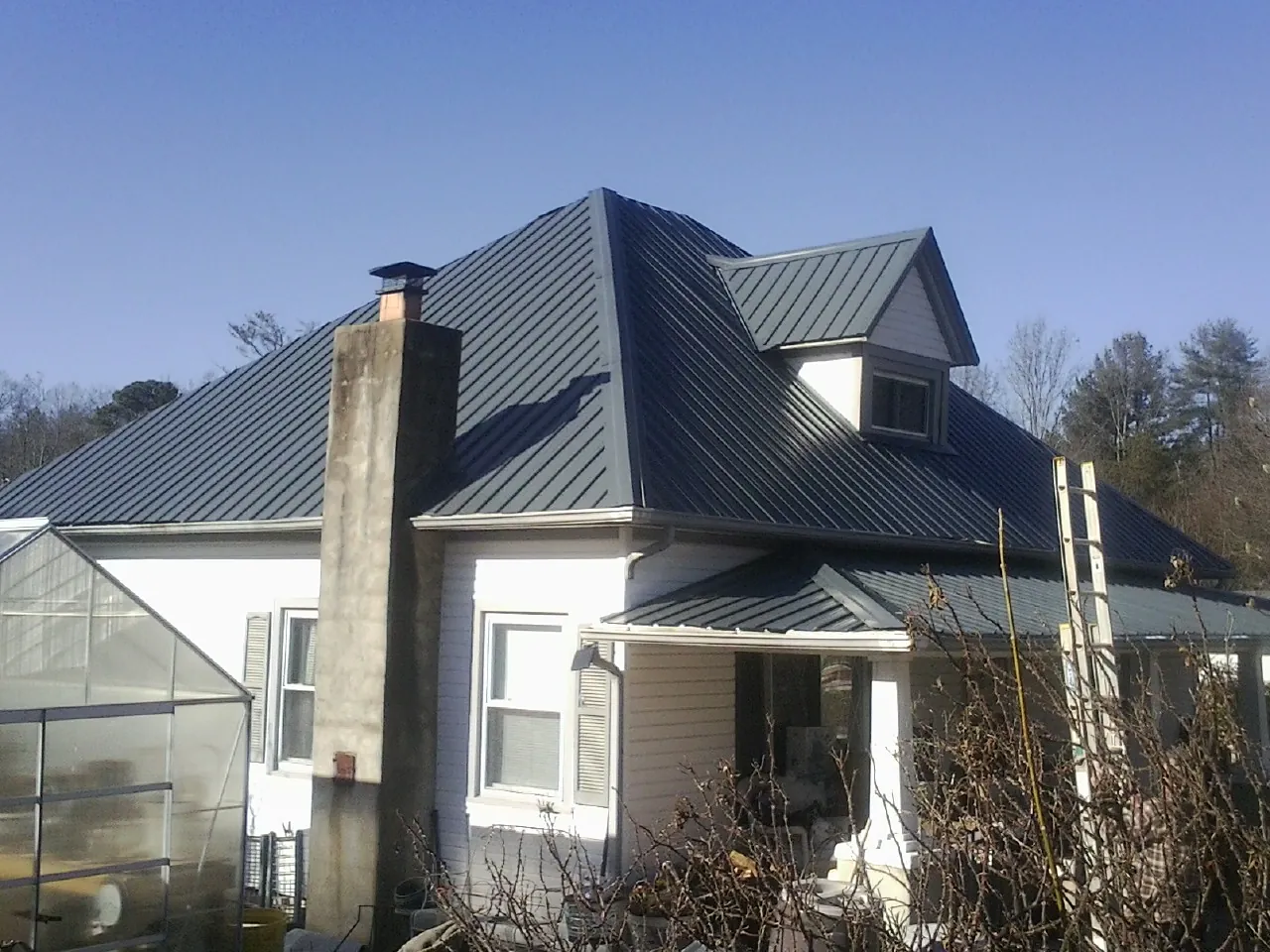 Dark blue standing seam metal roof on a white farmhouse with dormer — Slate & Tile Roof Repair by Roofing Brothers in Stevinson