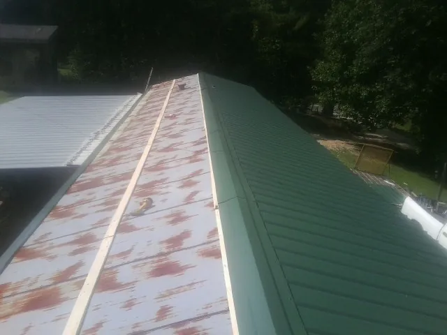 Old rusted panels beside newly installed green metal roofing — Wind Damage Roof Repair by Roofing Brothers in Stevinson