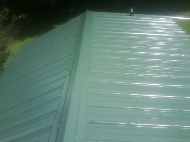 New green metal panels meeting at the ridge of a roof — Flat Roof Repair work by our crew in Stevinson
