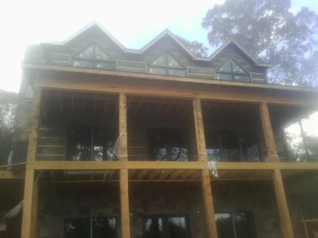 Dormers and porch framing on a large log home under construction — Roof Coating work by our crew in Stevinson