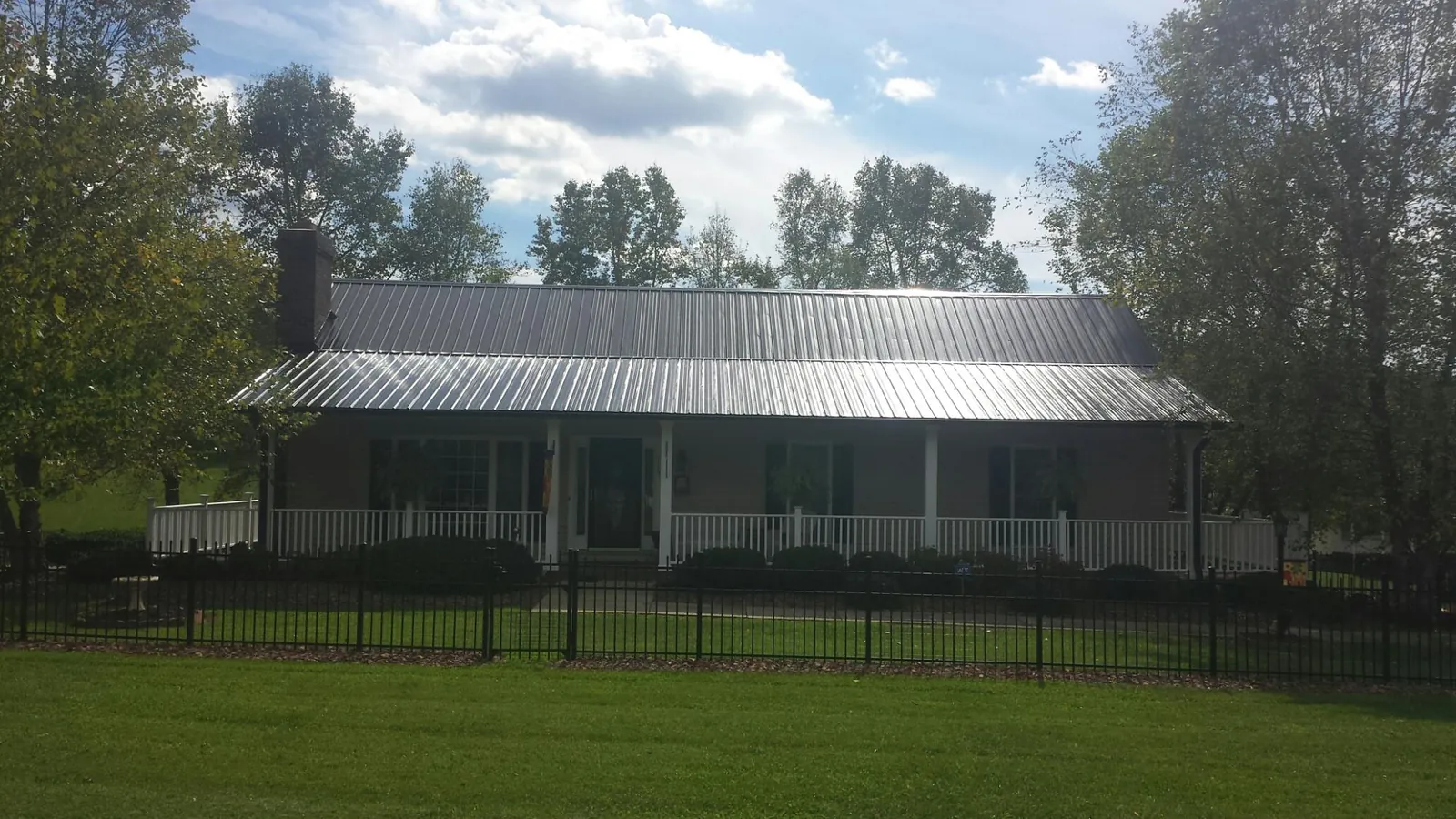 Gray metal roof on a brick ranch with a full width front porch — Gutter Guard Installation work by our crew in Stevinson