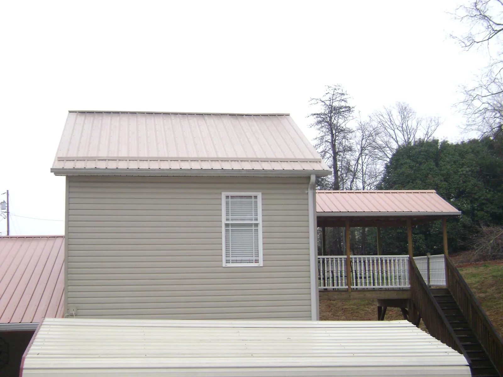 Tan metal roofs on a two story addition and attached porch, from a Roof Replacement job in Stevinson
